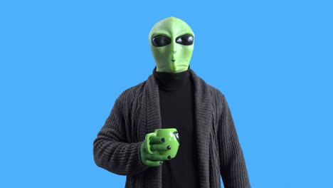 alien in a stylish black cardigan walks around the spaceship with a mug of hot drink, walks and looks around, drinks coffee. chromokey. morning routine.