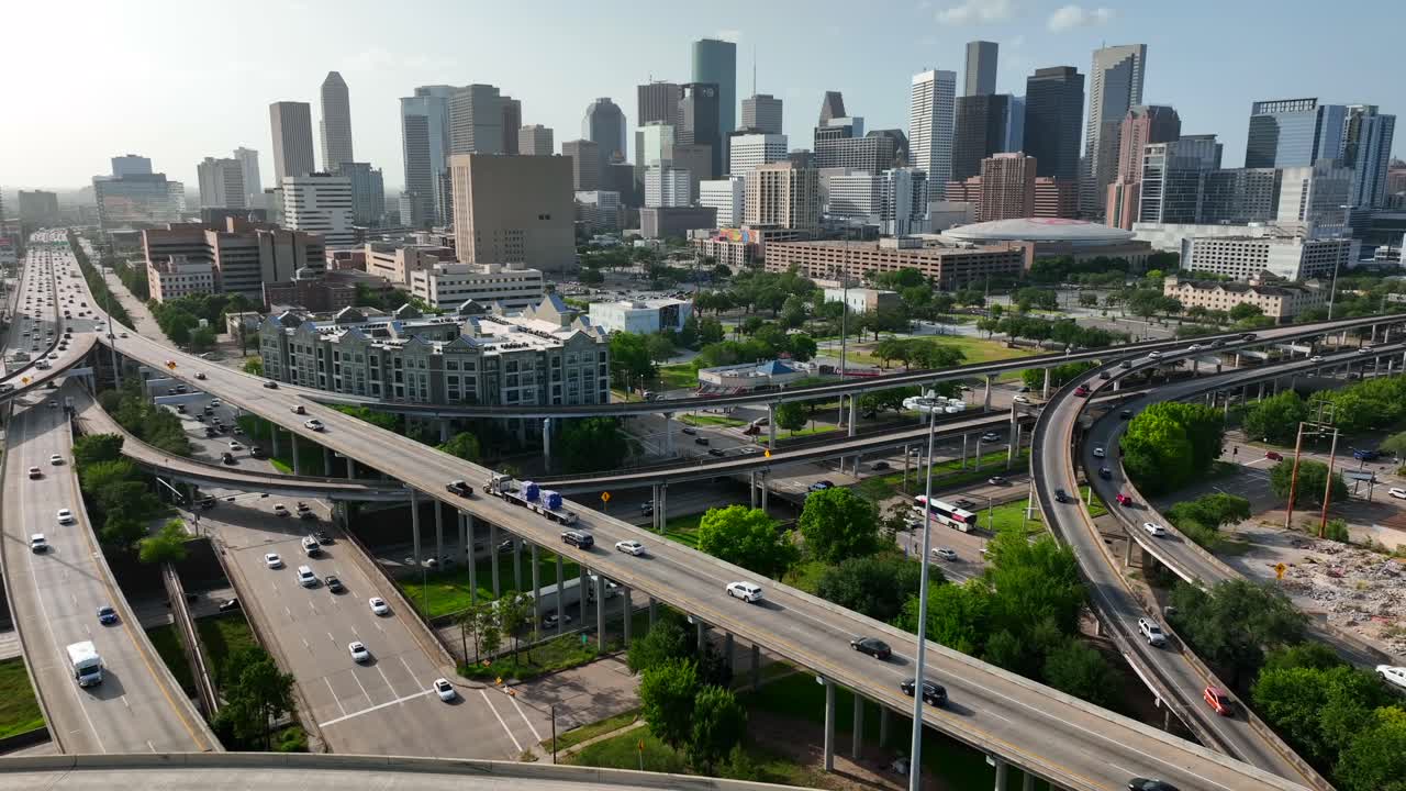 Rekaman udara tarik mundur yang menampilkan cakrawala pusat kota Houston Texas dan lalu lintas antarnegara bagian di jalan raya bebas hambatan.