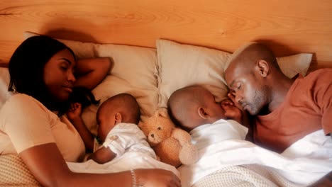 young parents with little children sleeping and embracing in bed