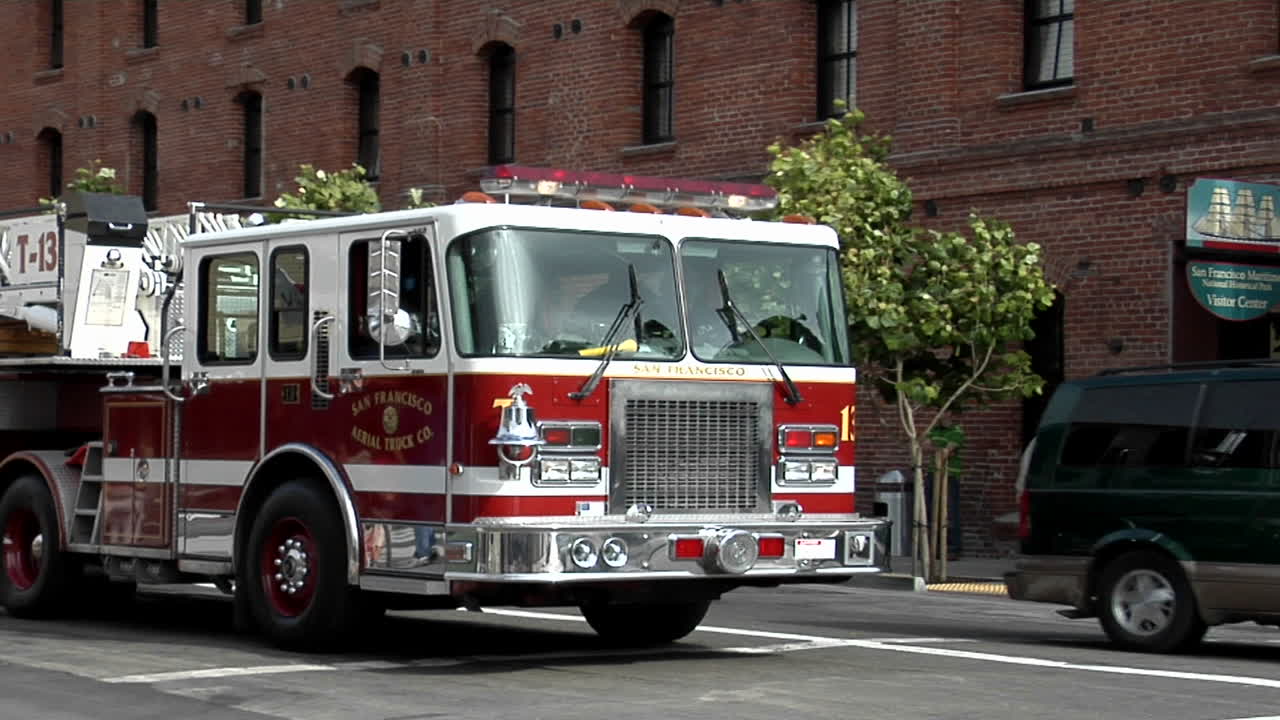 пожарная машина с крюковой лестницей поворачивает за угол в городской черте