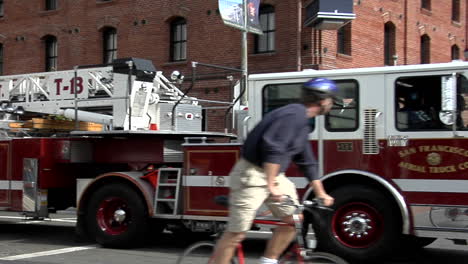 un camión de bomberos hookandladder dobla una esquina en un área urbana