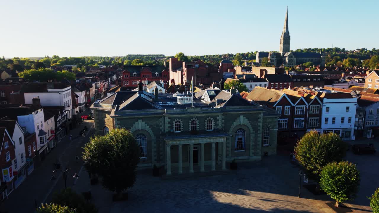 Vista aerea con drone della Guildhall di Salisbury e della piazza del mercato con la Cattedrale di Salisbury che svetta sul centro storico della città nel Wiltshire, Inghilterra