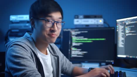 focused programmer engaged in coding work at dual computer setup in a dimly lit environment, showcasing the intensity of software development and debugging process
