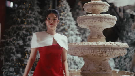 woman in red dress near fountain during christmas