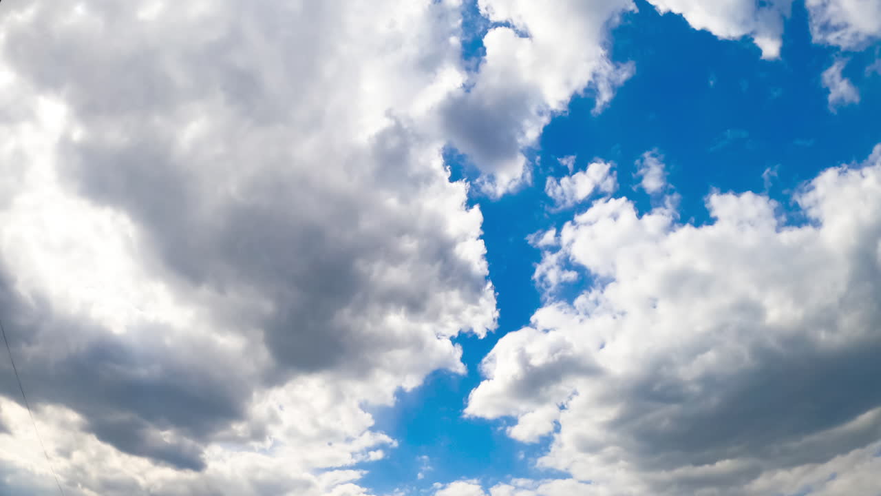 Two big clouds meet in the horizon forming one. Sky being covered with cloudscape. View from below. Timelapse.
