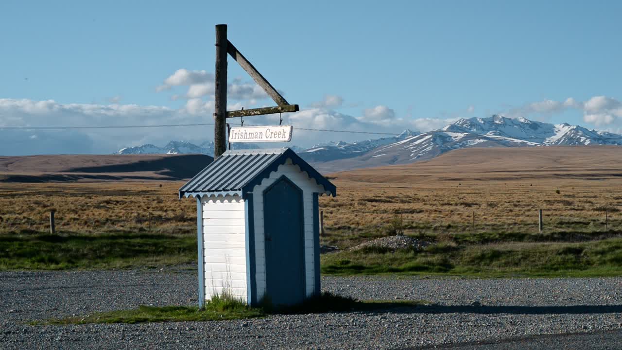 toma estática de la cabaña de la estación irishman creek con montañas cubiertas de nieve en el fondo en el pintoresco mackenzie, nueva zelanda