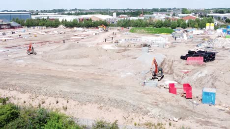 UK-town-housing-development-working-foundation-construction-site-aerial-view-low-right-dolly