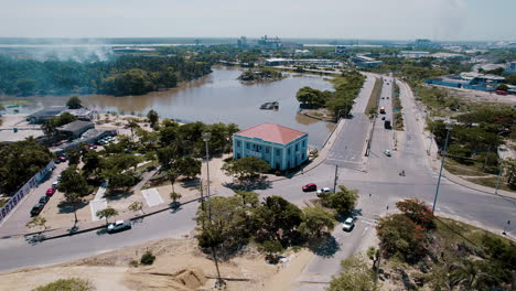 Aerial-view-of-the-charming-small-Blue-House,-affectionately-known-as-Ministerio-de-Cultura,-with-a-serene-lake-in-the-background