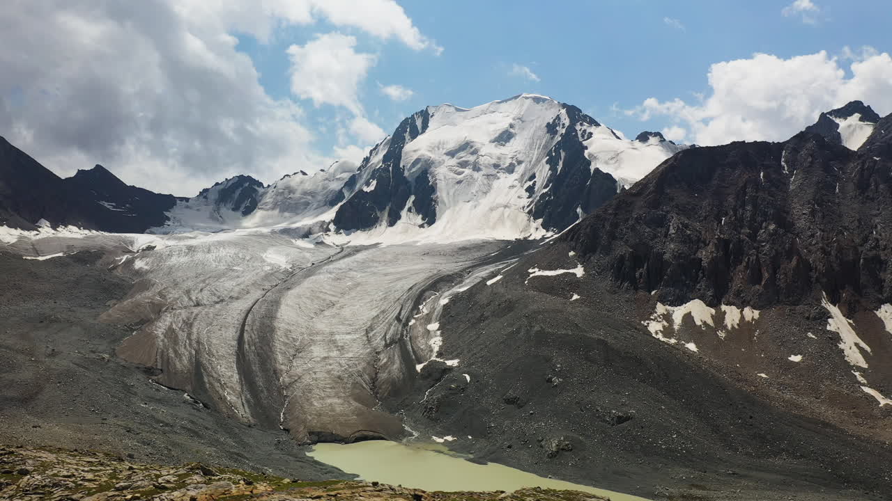 toma aérea de un dron de una montaña cubierta de nieve y un glaciar a lo largo del lago ala-kol en kirguistán