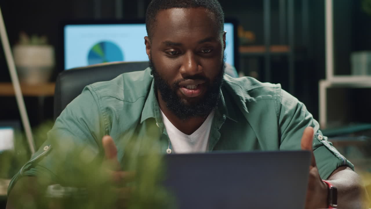 primo piano un serio uomo d'affari afro che discute di un progetto tramite video chat in casa