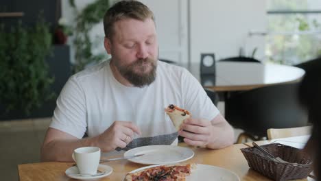 man eating pizza in a cafe