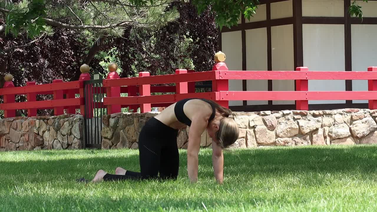 A young woman works out in a park as she flexes her muscular core. Yoga as a part of her health and wellbeing