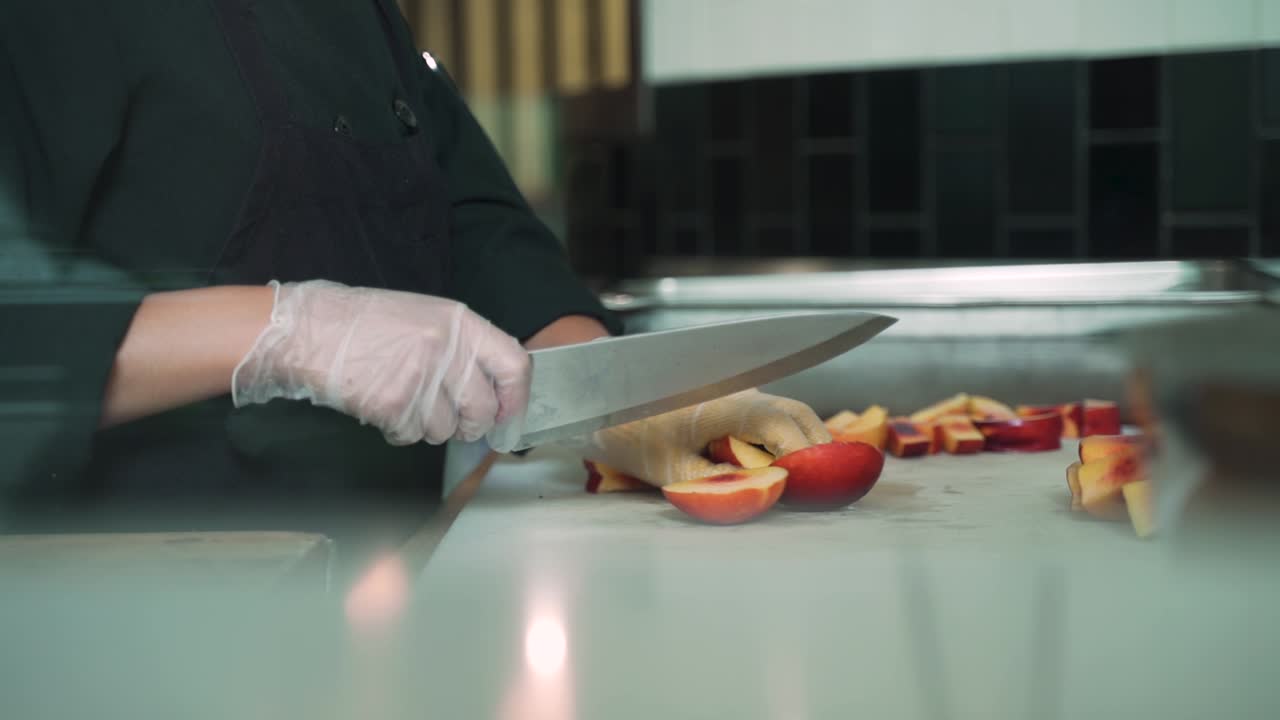 Lead chef is preparing and cutting peaches in half to grill and serve for the restaurant.
