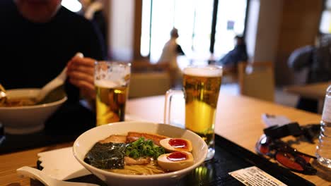 persona comiendo ramen y bebiendo cerveza