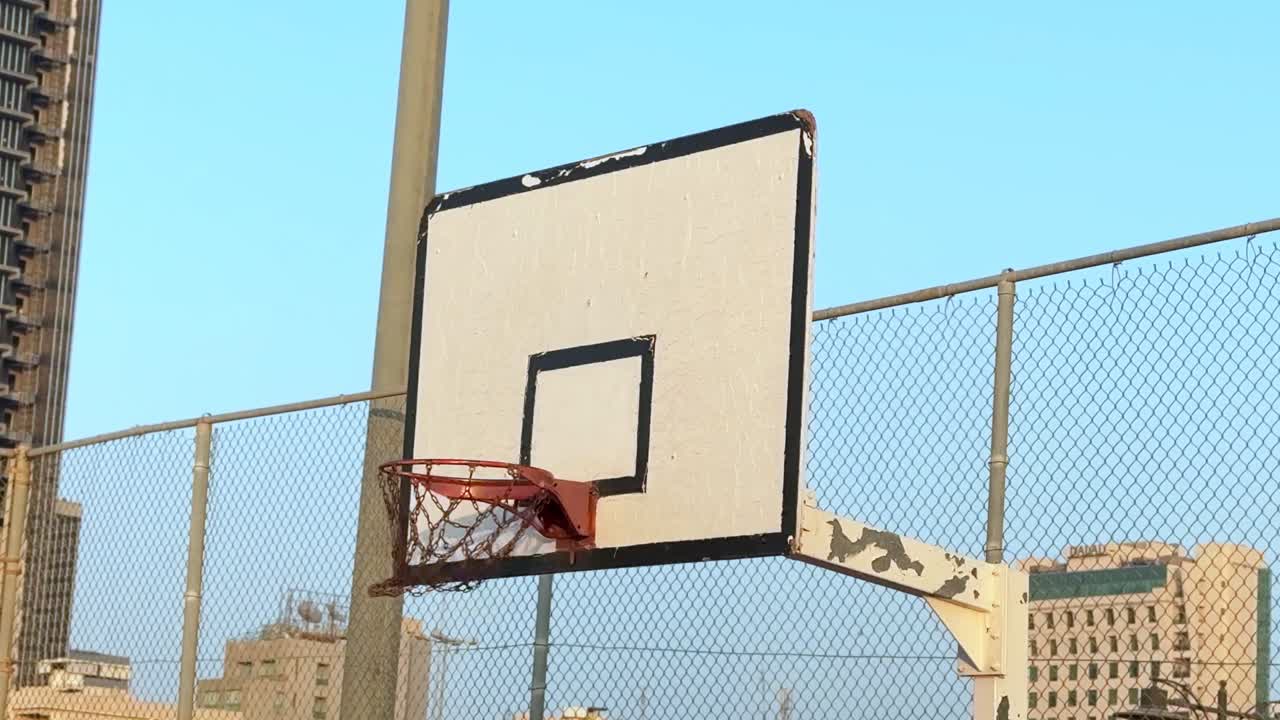Basketball hitting the hoop on a vintage outdoor court with city skyline. Urban sports moment ideal for ads, promos, and creative storytelling.