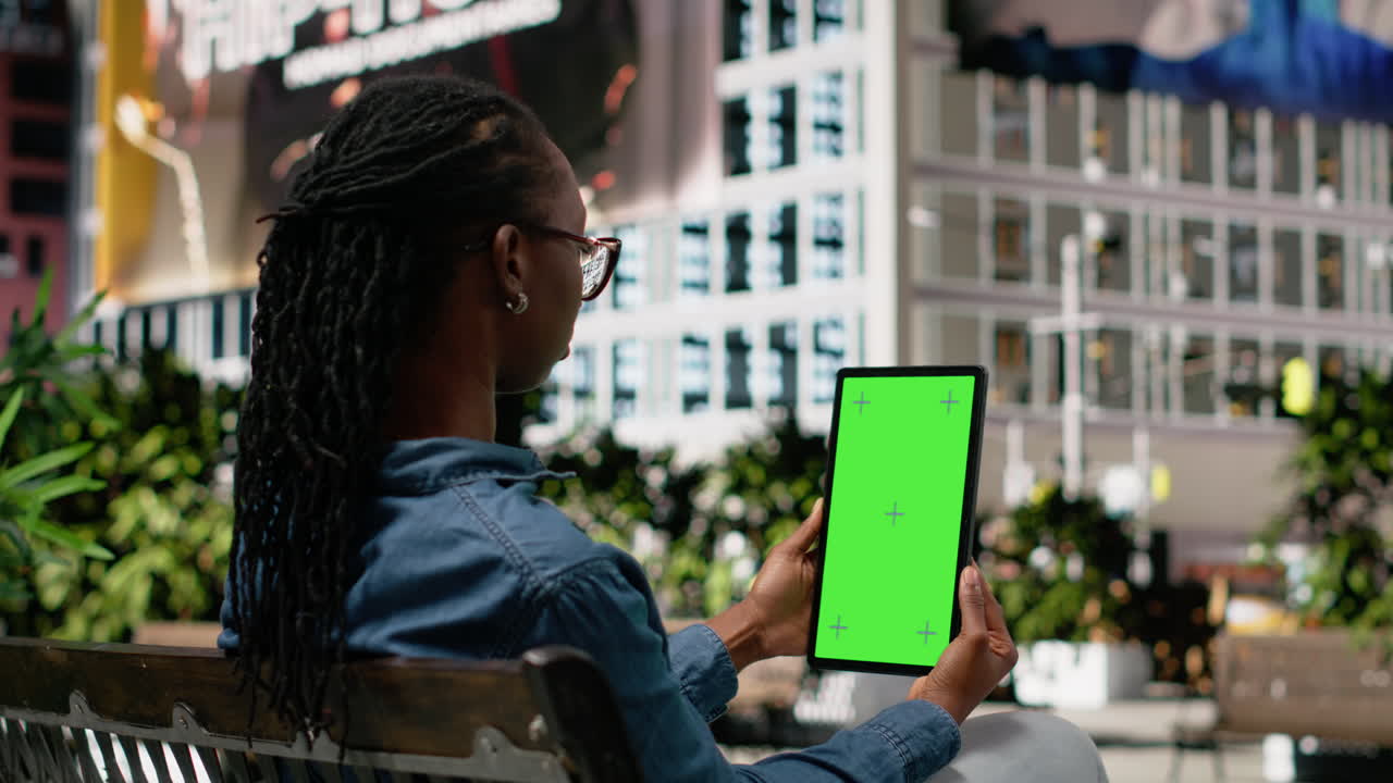 Mockup tablet vertikal terisolasi, diletakkan di bangku taman, dengan seseorang yang sedang bersantai.
