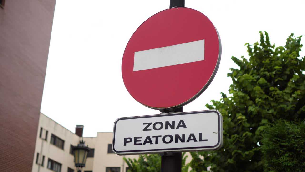 Road sign PEDESTRIAN AREA with an inscription in Spanish and ENTRY PROHIBITED
