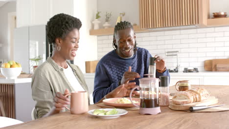 enjoying breakfast together, african american couple smiling and talking at kitchen table