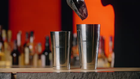 bartender adding ice to a cocktail shaker