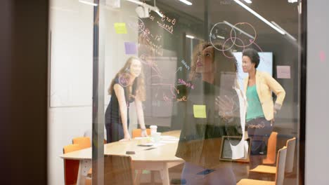 diverse businesswomen having meetings and brainstorming on glass wall at office, in slow motion