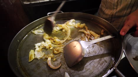 Local-Thai-cooks-Pad-Thai-on-a-street-food-market-in-a-big-pan,-handheld