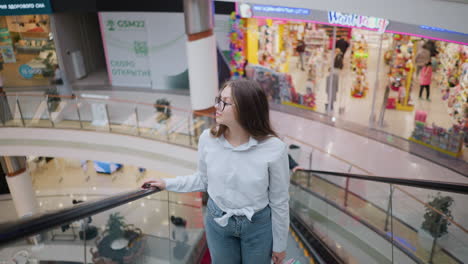 lady on ascending escalator in large mall, glancing around while surrounded by other shoppers and colorful store displays, capturing the lively atmosphere of urban shopping