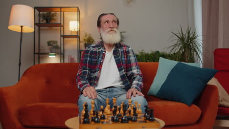 focused senior grandfather man playing chess leisure board game alone, domestic activity at home