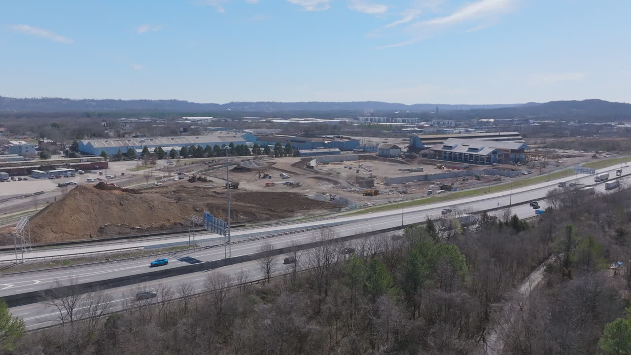 Wide aerial footage in the winter of a busy highway with a large construction site behind it in Chattanooga, Tennessee.