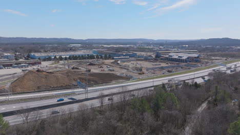 wide aerial footage in the winter of a busy highway with a large construction site behind it in chattanooga, tennessee.