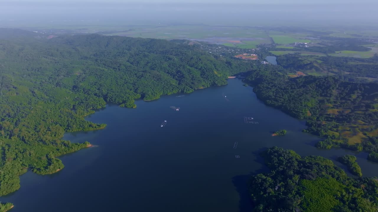 Aerial wide shot of idyllic landscape with reservoir. Rincon Dam in Dominicen Republic. Boat with foggy sky.