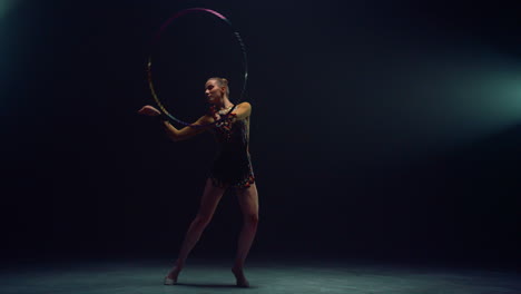 flexible gymnast spinning hula hoop. young woman practicing rhythmic gymnastics