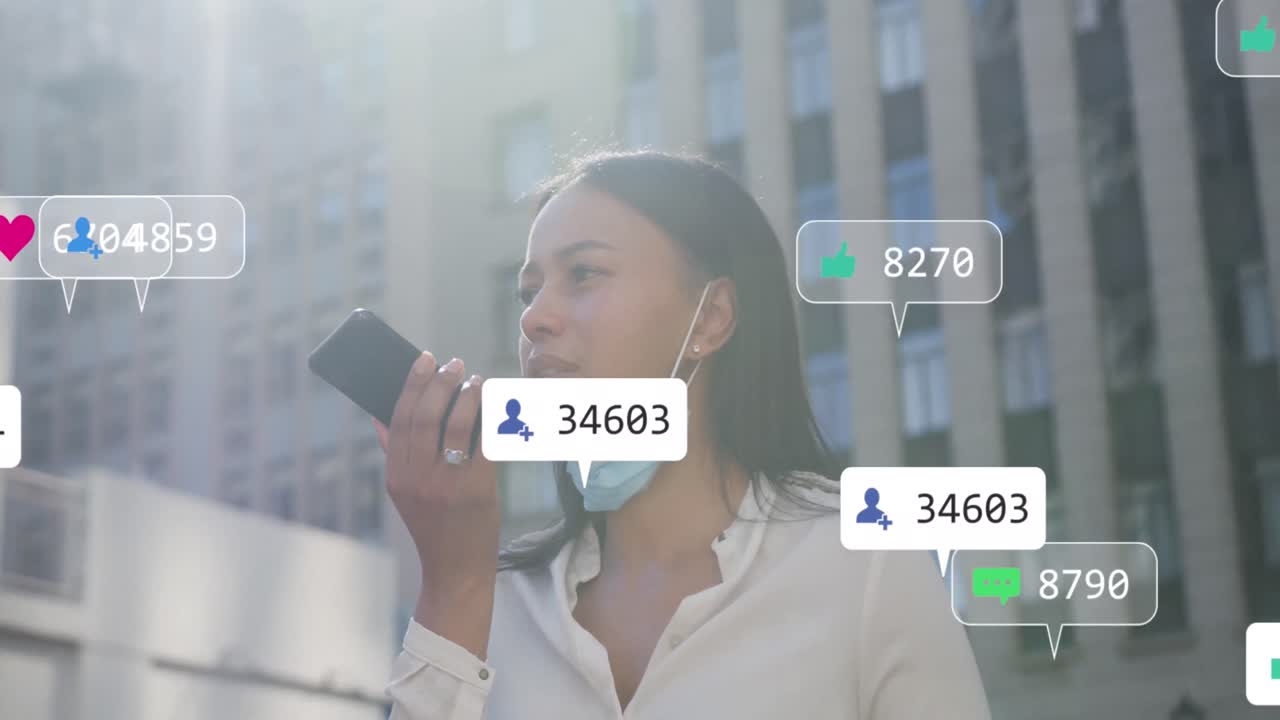 스마트 폰을 사용하여 얼굴 마스크를 쓴 두 인종 여성에 대한 소셜 미디어 아이콘과 숫자의 애니메이션