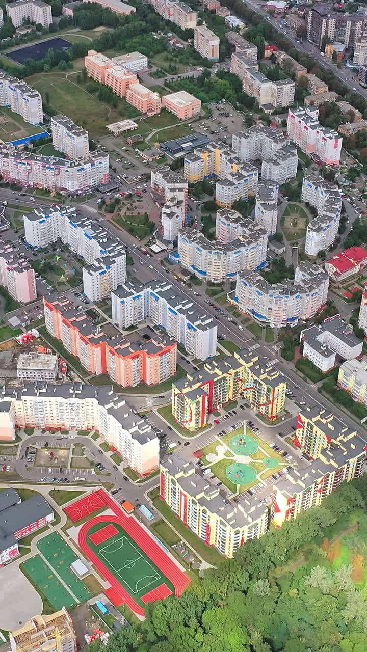 Urban landscape with green plantings. High-rise housing apartments of a new residential complex in modern city district. Aerial view. Vertical video