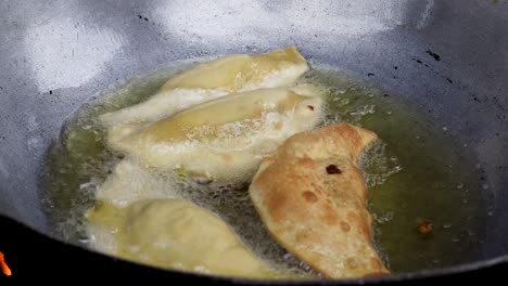 delicious homemade empanadas being fried in a pan of boiling oil