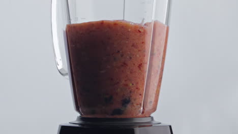 cóctel de bayas de frutas mezclándose en la licuadora de cerca. mezcla orgánica girando en el mezclador