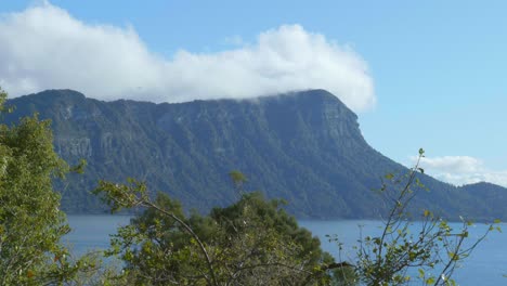 captivating footage of billowing clouds gracefully hovering over a majestic mountain, painting a serene and awe-inspiring natural tableau