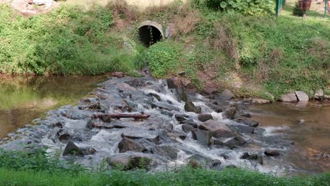 sewage pipe outflow into river, water pollution and ecology concept, urban wastewater system