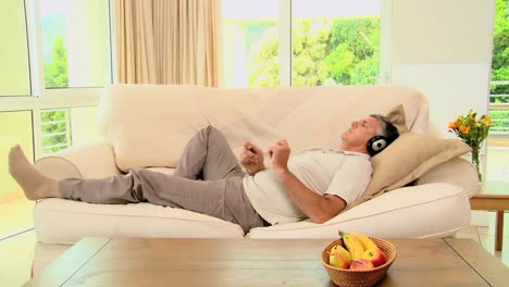 Man-lying-on-sofa-enjoying-music-with-headphones