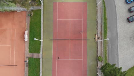 aerial shot of 2 vs 2 tennis on clay court, outdoor recreational sports facility