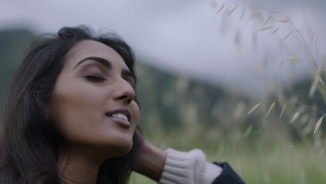 close-up-young-indian-woman-hiker-running-hand-through-hair-enjoying-relaxed-outdoors-travel-adventure-in-beautiful-countryside-landscape-independent-female-tourist