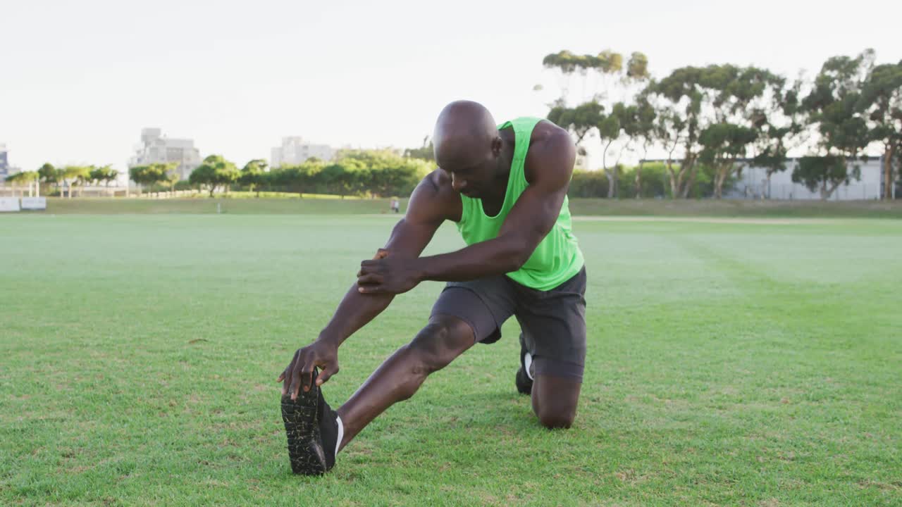 Fit african american man exercising outdoors, stretching