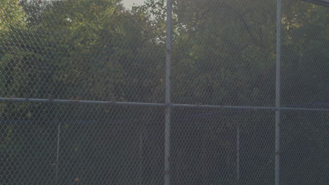 sunlight hits a fence outside on a school playground tracking left down the fence