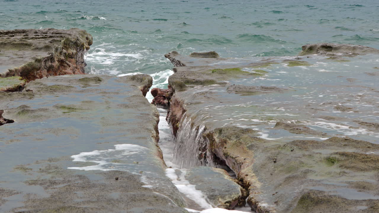 slowmotion shot of ocean water falling into a crevice created at Punta Bruja