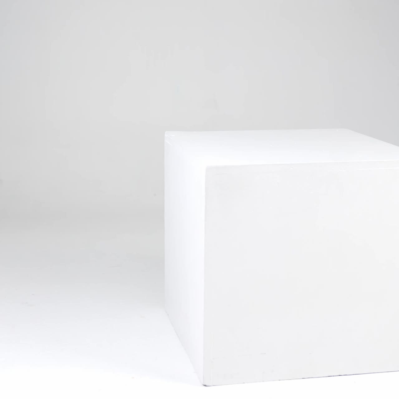 Female model in black tractor boots and mini skirt comes up to a white cube in studio. Girl sits on the cube showing the stylish footwear