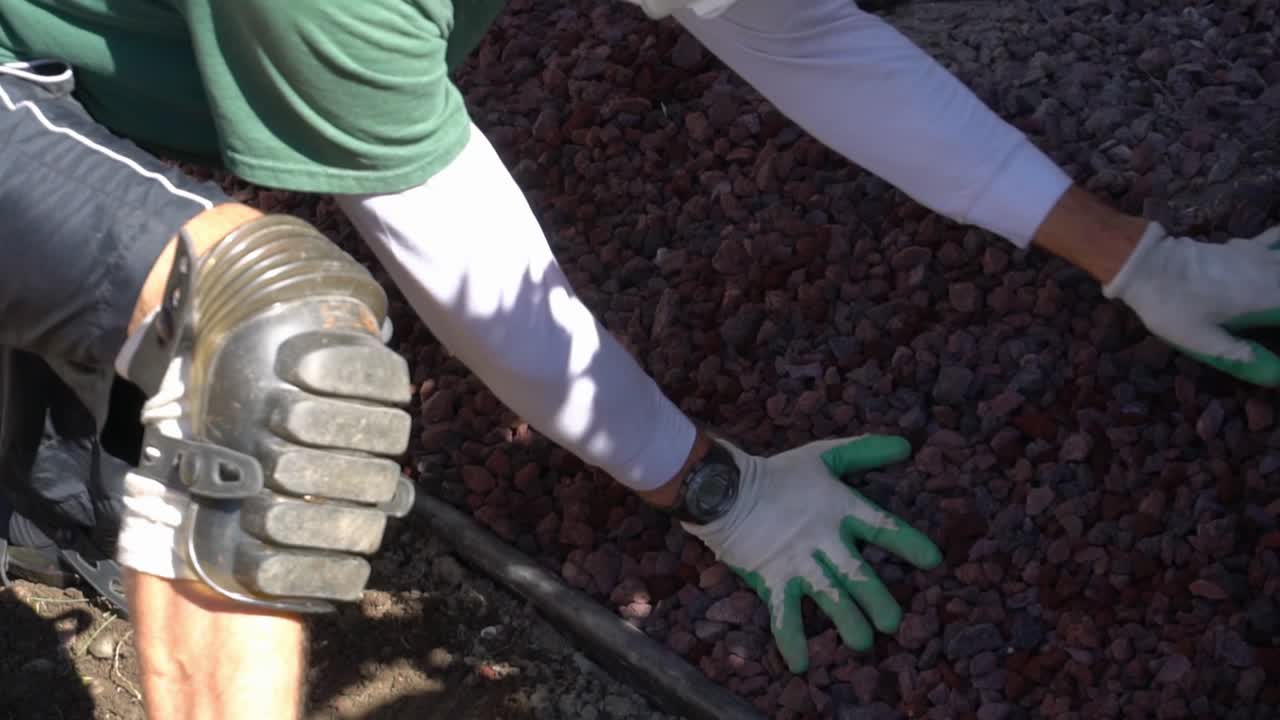 paisajista extendiendo rocas de lava en el jardín