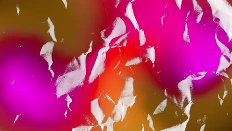 trozos de papel blanco rasgados moviéndose sobre el resplandor rojo y rosa en un fondo oscuro