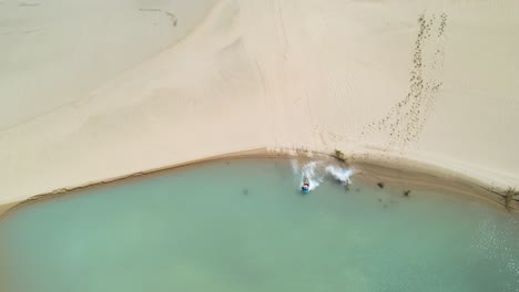 sandboarding from sand dune to small lake at te paki sand dunes, new zealand adventure, drone shot