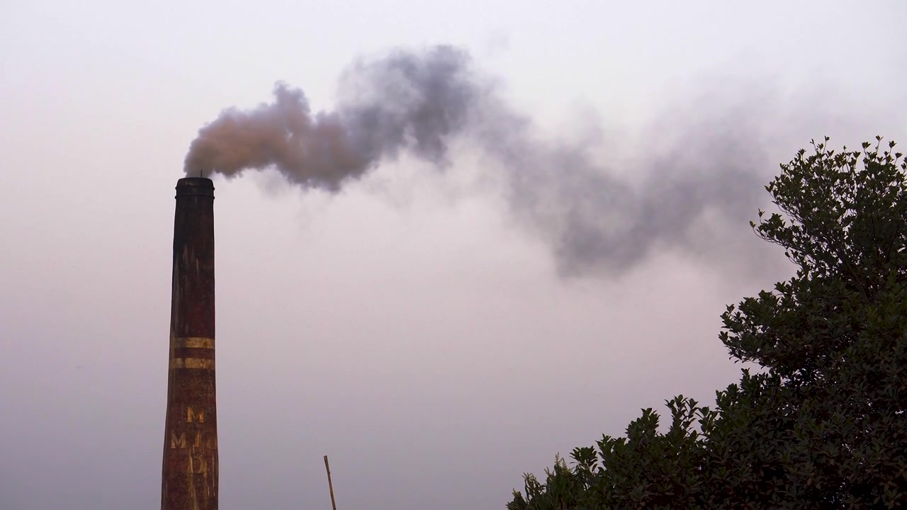 Industrial smoke or emissions billowing from a brick field chimney or smokestack, air pollution concept