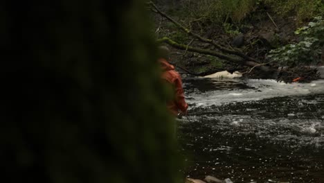 Toma-Lenta-Y-Reveladora-De-Un-Pescador-Lanzando-Su-Caña-Giratoria-A-Un-Río-Que-Fluye-Rápidamente.