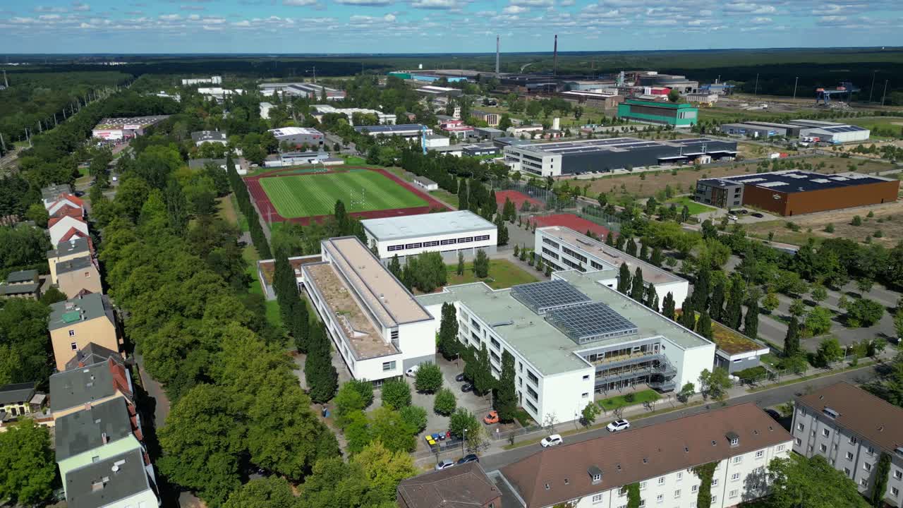 sports facilities at Hennigsdorf high school, including a soccer field, running track and other buildings in residential areas. Best aerial view flight panorama orbit drone